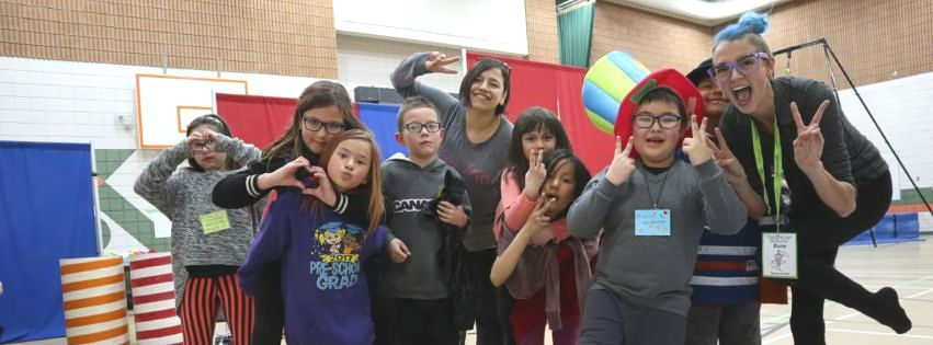 A photo of kindergarten to grade 5 students in a northern Saskatchewan school smiling and laughing with colourful props.