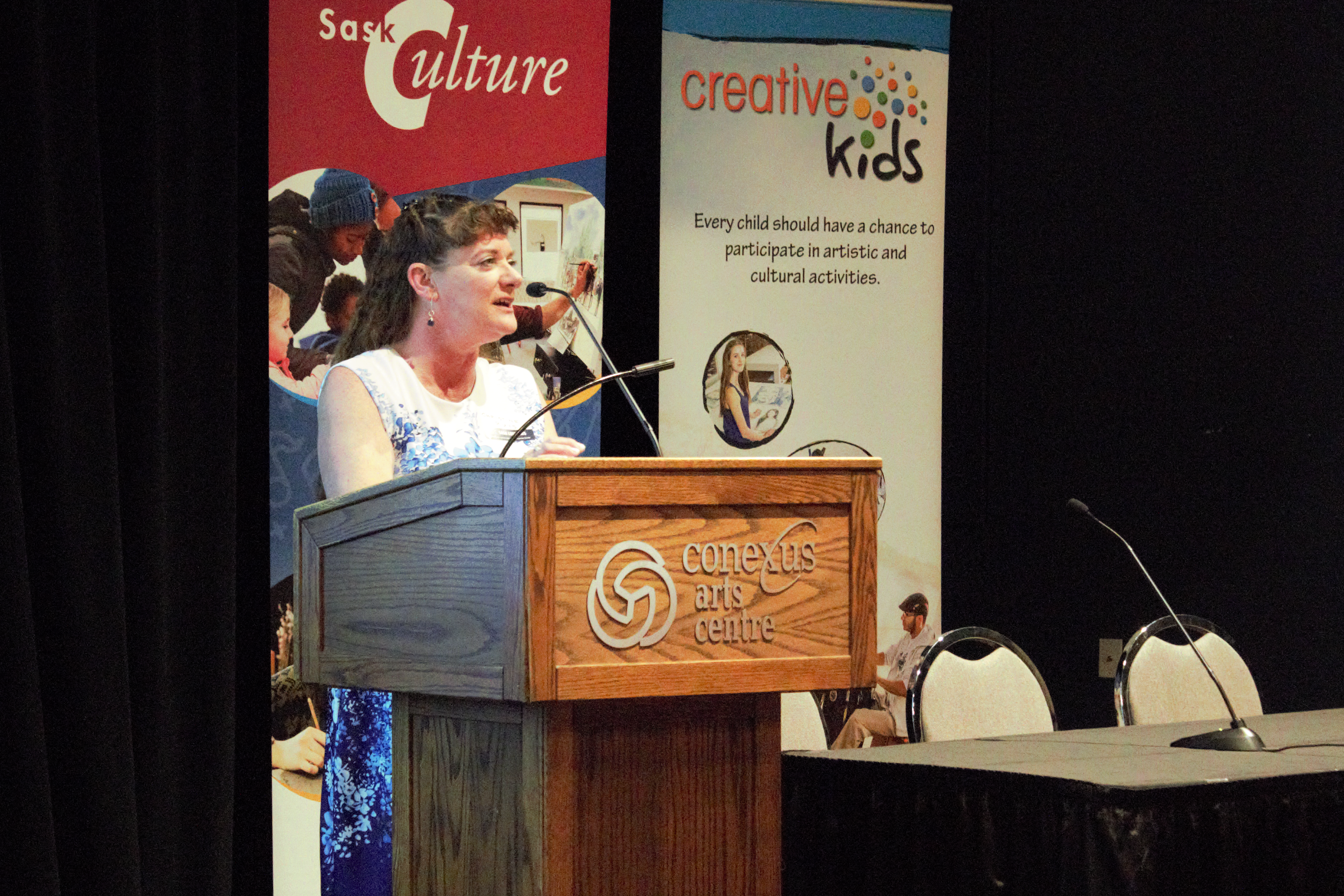 A photo of Christine Ruys speaking at a podium at the 2023 AGM.