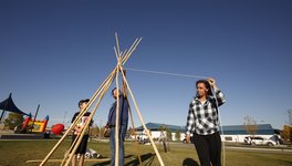 A photo of three people erecting a tipi.