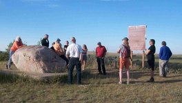 A photo of a group of people gathered in a field participating in one of the Saskatchewan History and Folklore Society-hosted walks along a historic trail.