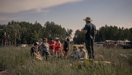A photo of attendees of the Ness Creek Music Festival  participating in a guided forest walk, listening to someone speak.