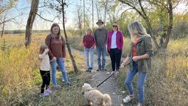 A photo of a small group of people and a dog visiting the Saskatoon Afforestation areas.