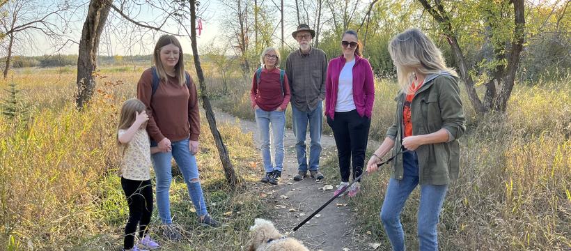A photo of a small group of people and a dog visiting the Saskatoon Afforestation areas.
