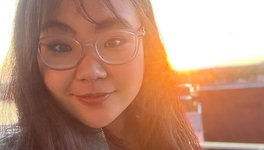 A photo of Emily Tang looking at the camera smiling, with sunset background.