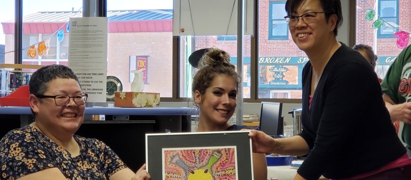 A photo of Harriet Roy (on the left), a long-time volunteer of SAS, presenting artwork.