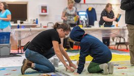 A photo of Monique Martin making an art installation with young kid at her 2023 Nuit Blanche Saskatoon installation.