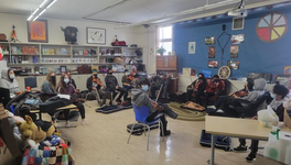 A photo of kids in a classroom learning to play the fiddle.