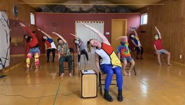 dancers in colourful clothing lead movement exercises while seated