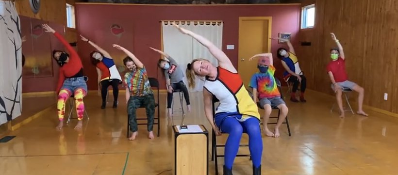 dancers in colourful clothing lead movement exercises while seated