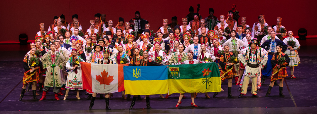 Volunteer performers posing on a stage at the United for Ukraine concert, holding up Canada, Ukraine and Saskatchewan flags.
