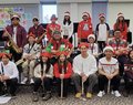 School band group photo with students in festive sweaters and Santa hats, holding instruments like saxophones, clarinets, and flutes.