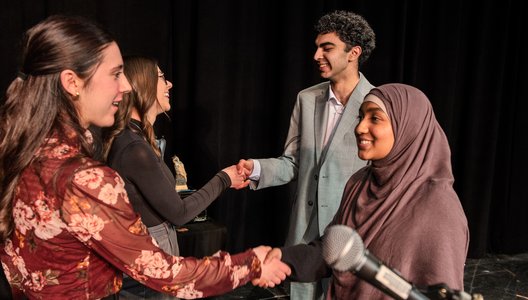 Four people shaking hands with each other.