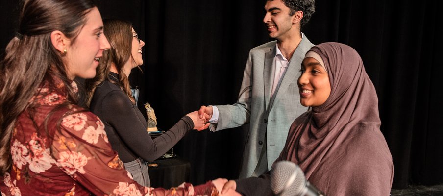 Four people shaking hands with each other.