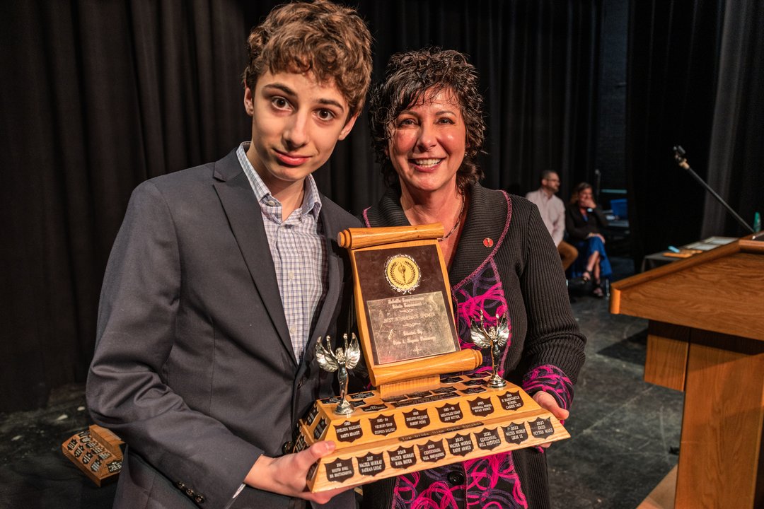 Photo of two people holding a trophy.