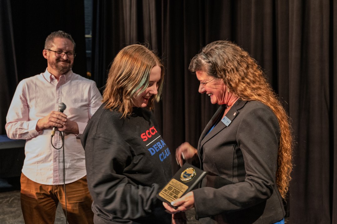 Photo of a debater being handed a plaque from a SaskCulture board member.