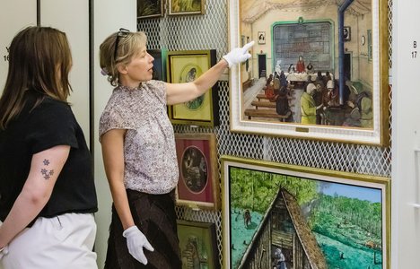 Photo: Dr. Jen Budney pointing out to one of the Kurelek's painting in the collection - A First Meeting of the Ukrainian Women’s Association, 1966