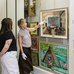 A photo of Dr. Jen Budney, Executive Director & CEO of the Ukrainian Museum of Canada, giving a tour of the collection and pointing out to one of the Kurelek's paintings.