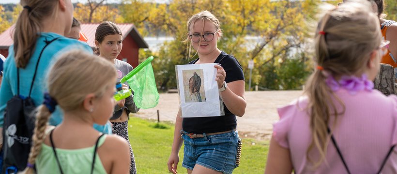 Group of children watching a volunteer displaying a picture of a bird.