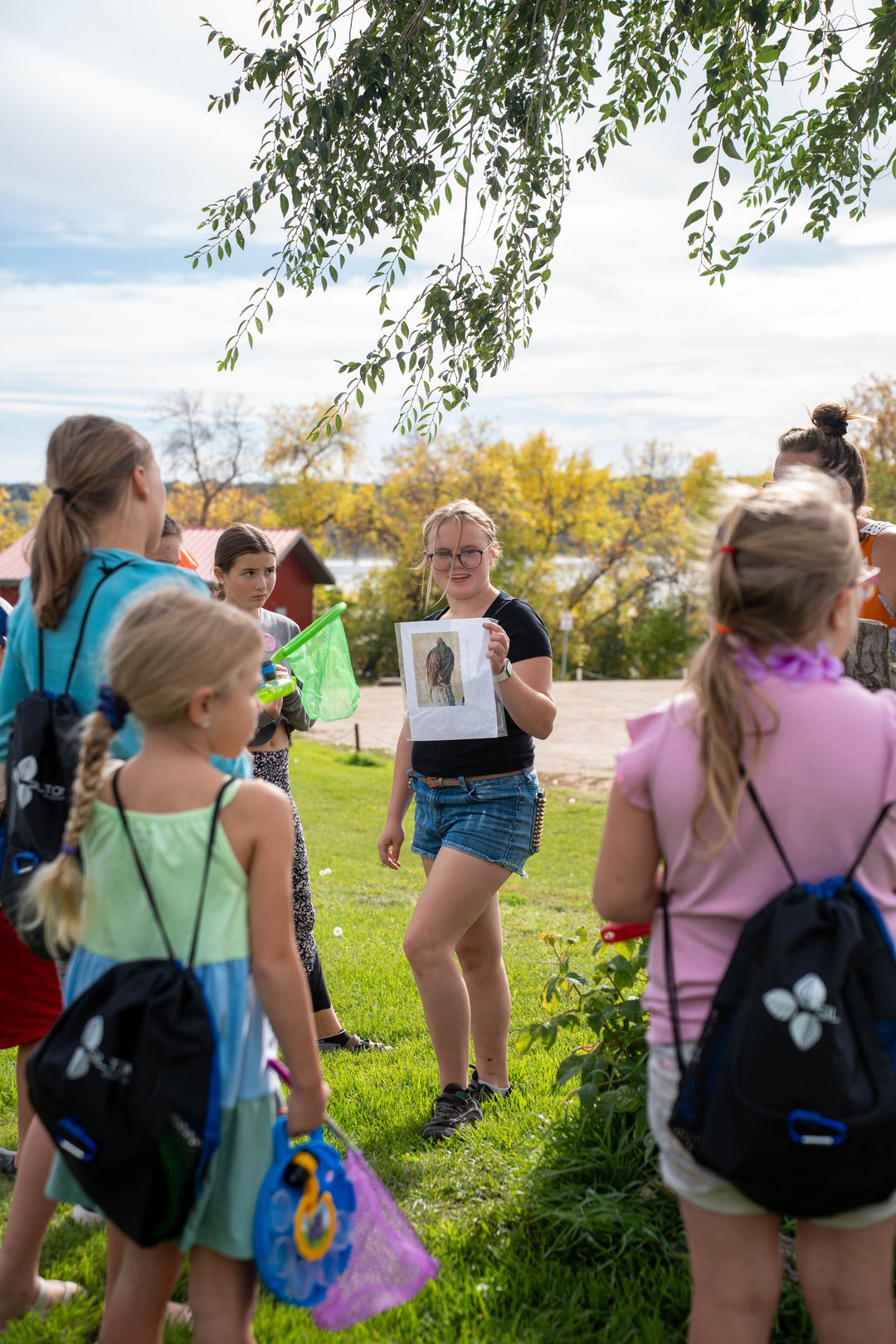 Group of youth looking at youth volunteer who is holding up a printed page of a bird.