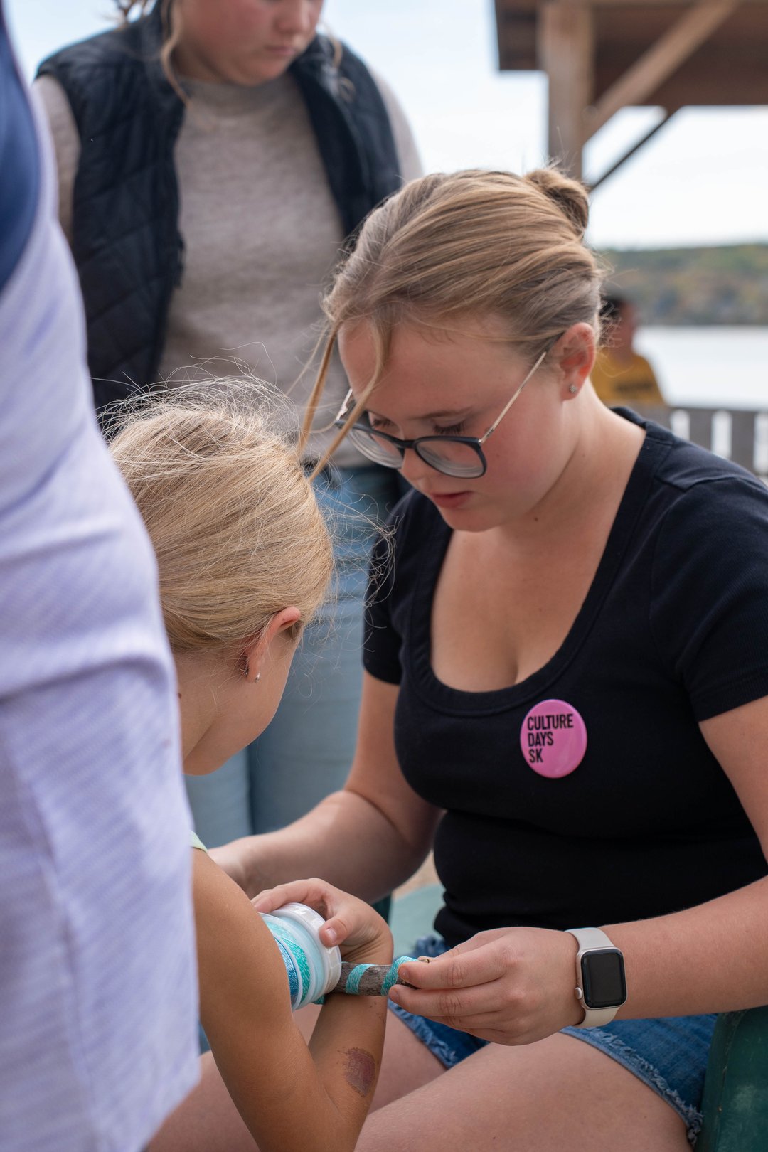 Photo of a youth volunteer helping a young participant create a craft.