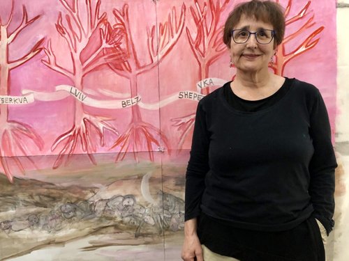 Photo of artist standing next to their painting