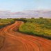 Oil painting by experience artist and teacher Laureen Marchand titled "Flow" depicting a winding red road leading to a Sasaktchewan horizon with a wide sky