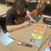 Youth participating in making pride signs using paint markers and cardboard.