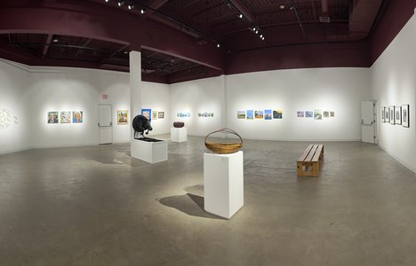 A panoramic image of a gallery space filled with paintings and sculptures made by community members.