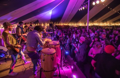 Photo of band preforming on the stage with a standing crowd listening