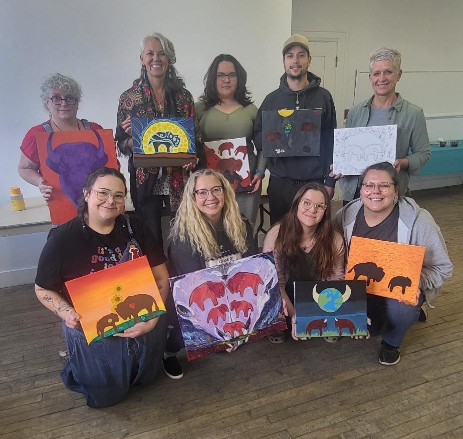 Photo of a group standing together with their paintings