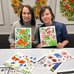 Photo of two workshop participants with their petrykivka paintings