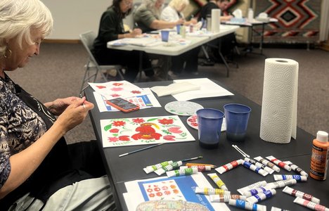 People sitting at tables creating Petrykivka