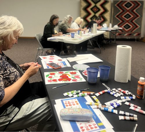 People sitting at tables creating Petrykivka