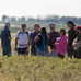 Image of a group of Indigenous students in a field listening to a speaker.