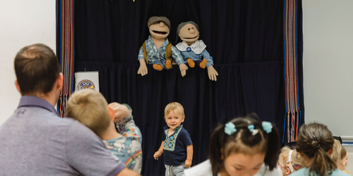 Puppet performance with a image of a child and family watching.