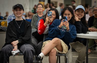 Diverse group of young people using their phones to take photos at a multicultural festival.