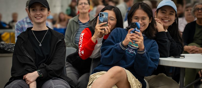 Diverse group of young people using their phones to take photos at a multicultural festival.