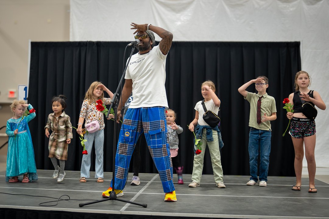 A man on a stage performing in front of a group of kids at a multicultural festival.