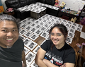 Artist Girlynne Gascon and her mentor Patrick Fernandez standing in front of many art prints.
