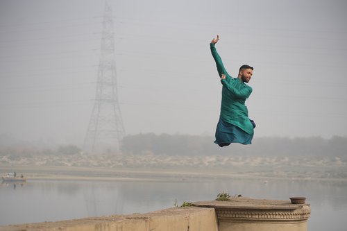 a dancer leaps into the air on a pier