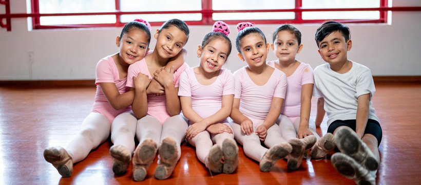 kids sitting in dance attire hugging