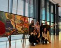 A photo of the women from different cultural backgrounds that came together to create an art piece, in front of the art piece.