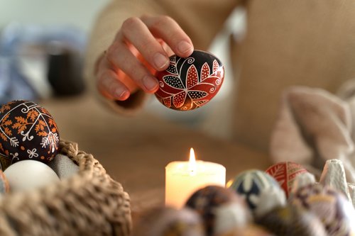 Female hand holding pysanka egg above the candle