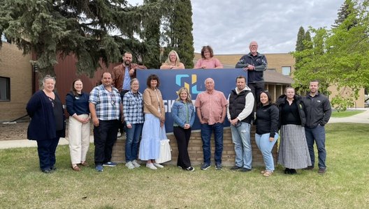 Photo of a group posing in front of a Sask Lotteries sign.