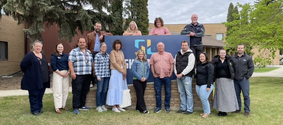 Photo of a group posing in front of a Sask Lotteries sign.